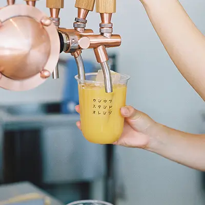 ジュースサーバーからオレンジの柑橘ジュースがなみなみと注がれているスライド写真