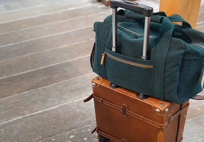 キャリーケースの上に乗せた紺色の帆布バッグの写真