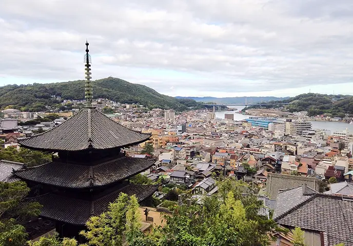 高いところから天寧寺の三重の塔、街並み、海を見渡す写真